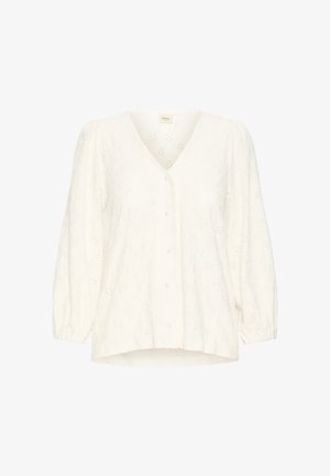 Blouse blanche avec un col en V, manches ballon et fermeture à boutons. Présente des motifs floraux découpés et une finition de tissu texturée.