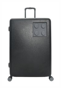 Svart resväska med en strukturerad yta, med ett LEGO-block mönster på ena sidan och ett utdragbart handtag. Fyra rullande hjul.