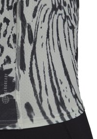 Nærbillede af en sort-hvid dyreprint sports-top med synlige sømme og et "AEROREADY" logo på åndbart stof.