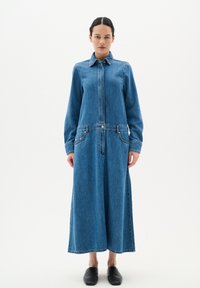 Sinine denimkleit, millel on krae, pikad varrukad ja eesne mööndus. Omab kahte küljetaskut ning pikk, voolav seeliku disain.