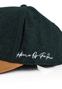 Green felt cap with a brown suede brim, featuring white embroidered text "Home Of The Brave" on the side.