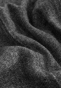 Dark gray herringbone patterned fabric with soft folds and visible woven texture in close-up view.