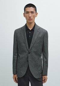 Gray textured blazer with notch lapels, single button closure, and front pockets, paired with a black polo shirt beneath.