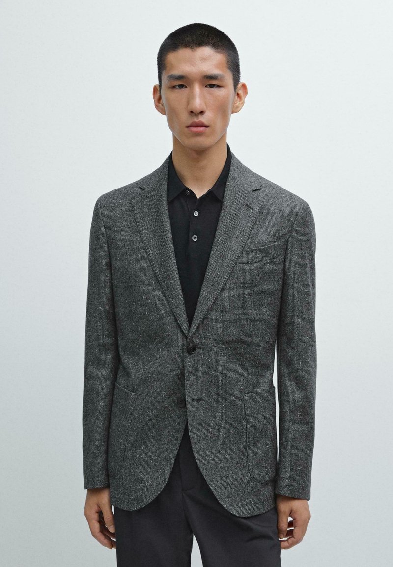 Gray textured blazer with notch lapels, single button closure, and front pockets, paired with a black polo shirt beneath.