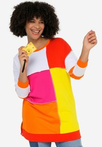 Pestrobarevná oversized mikina s patchworkovým designem v jasně růžové, oranžové, žluté a bílé barvě. Měkká tkanina s kulatým výstřihem.