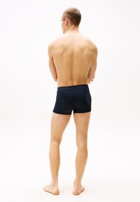 Marineblaue Stretch-Boxershorts mit flachem Bund, taillierter Passform und minimalen Details, von hinten getragen.