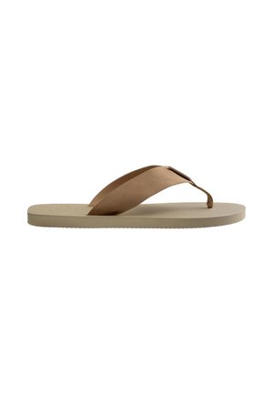 Infradito beige con suola lavorata e ampie fasce di tessuto marrone che formano un anello per le dita su sfondo bianco.