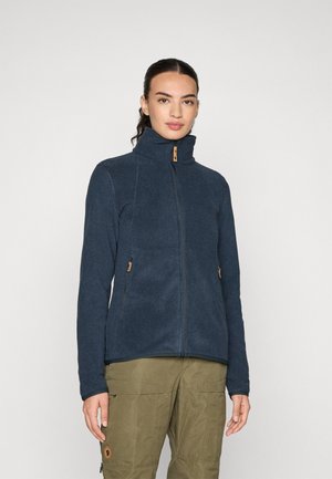 Navy fleece jacket with a high collar, zip closure, and two front zip pockets. Features tan accents on the zipper pulls. Smooth texture.