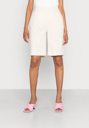 Beige op maat gemaakte shorts met een gladde textuur, een middellange snit en een rechte pasvorm, gecombineerd met roze haksandalen met kruislings gespen.