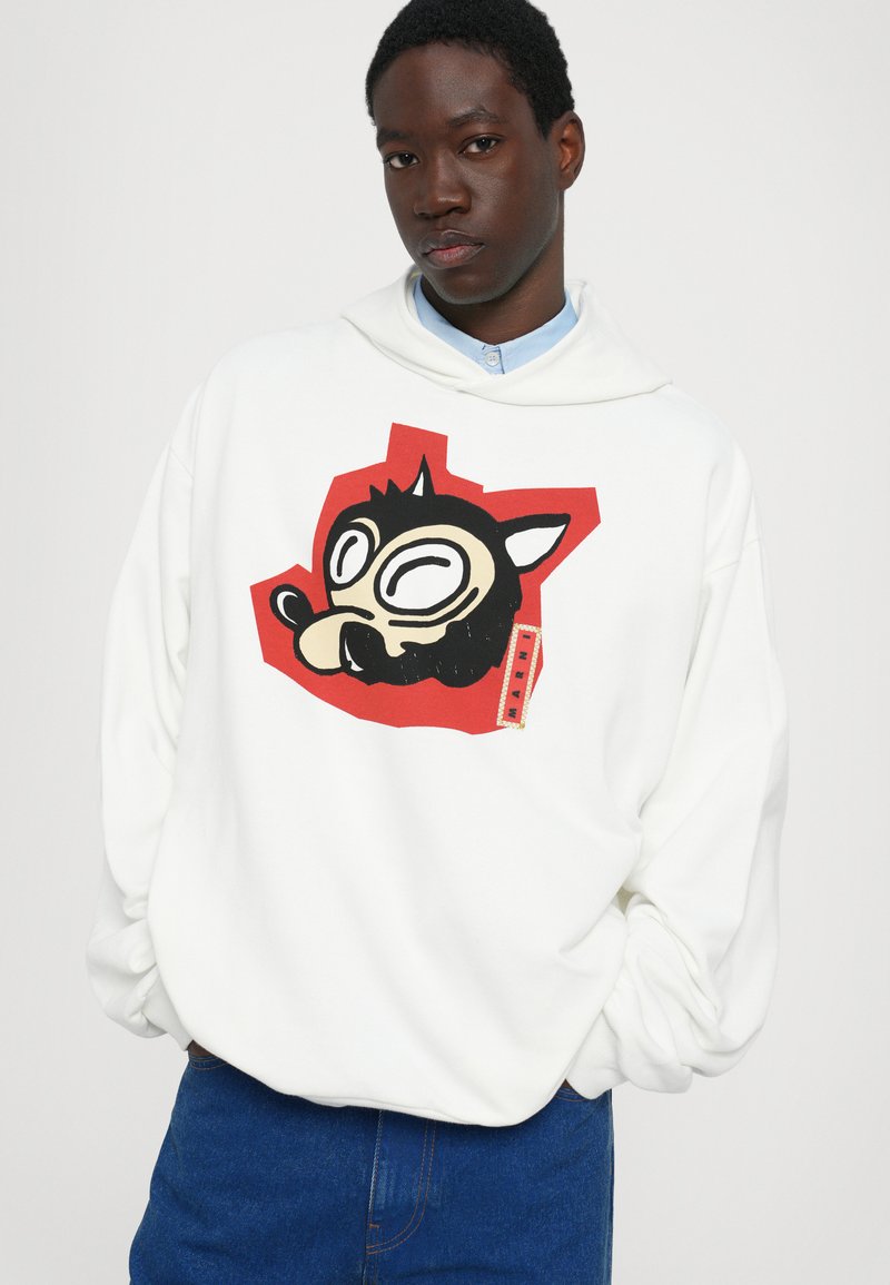 Hvid hættetrøje med en stor, farverig grafik af et tegneserieansigt med sort kant og rød baggrund. Blødt stof, afslappet pasform.