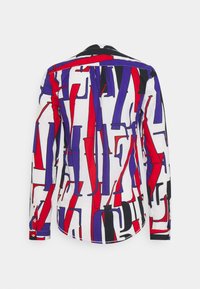 Långärmad skjorta med ett mångfärgat abstrakt mönster i rött, blått och svart på en vit bakgrund. Har rundad nederkant och knappade ärmslut.