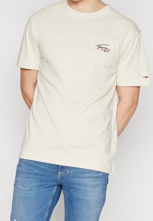Cream-colored cotton t-shirt with short sleeves, round neckline, and a small embroidered logo on the upper left chest.