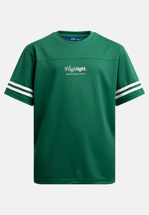 Vihreä urheilupaita, joka on valmistettu verkkomateriaalista. Siinä on valkoiset raidat hihoissa ja "Highlight"-logo etuosassa. Pyöreä pääntie, lyhyet hihat.