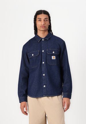 Dunkelblaue Jeanshemd mit zwei Brusttaschen, Druckknöpfen und einem kleinen Logopatch. Verfügt über einen Kragen und lange Ärmel sowie Kontrastnähte.