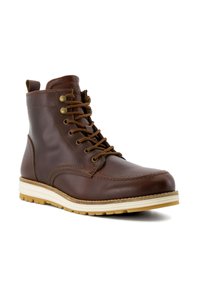 Brown leather ankle boot with lace-up design, reinforced toe, and contrast white rubber sole. Features gold-tone eyelets and stitching details.