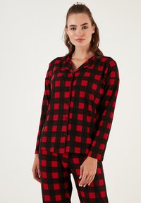 Conjunto de pijama de franela a cuadros rojo y negro, que incluye una camisa de botones de manga larga y pantalones a juego con una cinta elástica en la cintura.
