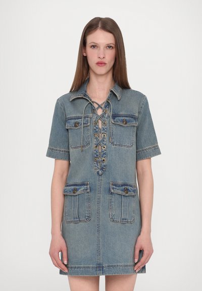 Denim dress featuring a collared neckline, short sleeves, lace-up front, and two front pockets with button accents. Light blue color.