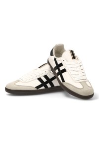 Zapatillas deportivas con parte superior de cuero blanco, acentos de ante negro y punta de ante gris. Presenta rayas negras y una suela de goma texturizada.