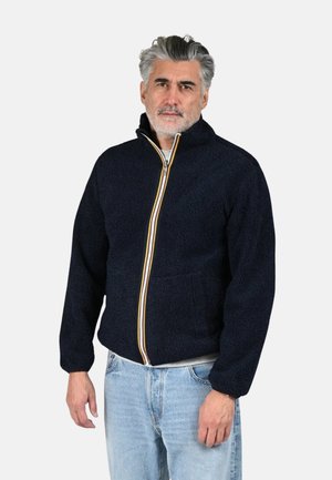 Giacca in pile blu navy con collo alto, cerniera integrale e dettagli a righe color crema, oro e ruggine; due tasche frontali, tessuto strutturato.