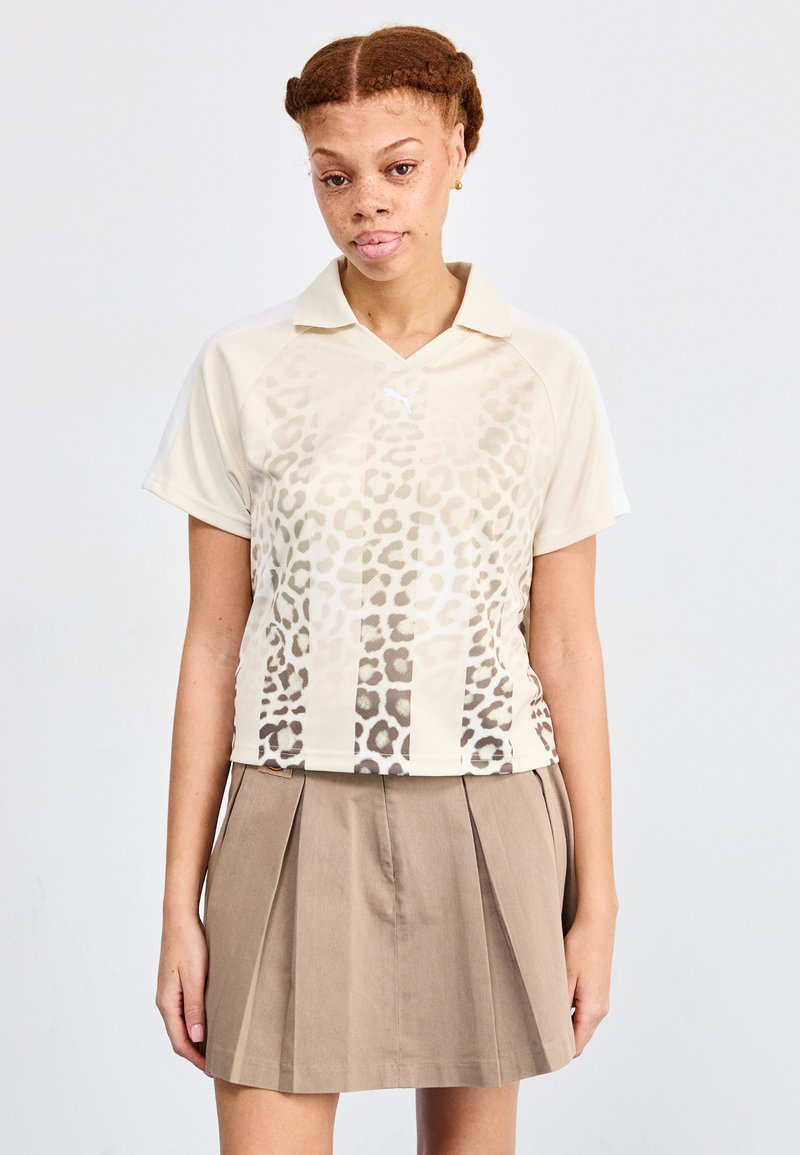 Polo com padrão de leopardo, de mangas curtas e gola, feito de um tecido leve. Combinado com uma saia plissada bege.