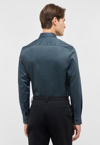 Marineblauw overhemd met kleine witte stippen, met een getailleerde pasvorm, lange mouwen en een klassieke kraag. Gemaakt van een katoenmix.