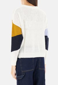 Maglione lavorato a maglia bianco con motivi a blocchi di colore in senape, blu navy e azzurro chiaro. Presenta un collo rotondo e polsini a coste.