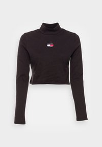 Musta pitkähihainen lyhyt turtleneck-paita, jossa on pieni Tommy Jeans -logo keskellä rintaa.