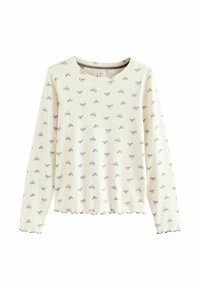 Cream long-sleeve top with a ribbed texture and an all-over grey bow pattern. Rounded neckline and scalloped hem detail.