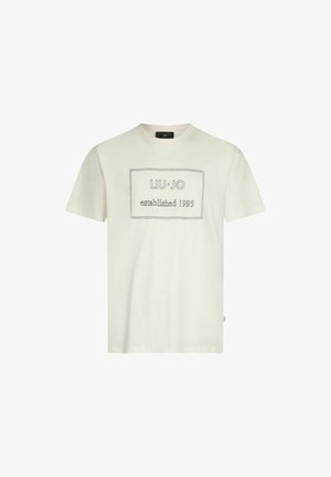 T-shirt in cotone color crema chiaro con maniche corte. Presenta un'etichetta grafica rettangolare con cuciture in contrasto che dice "LIU·JO established 1995."
