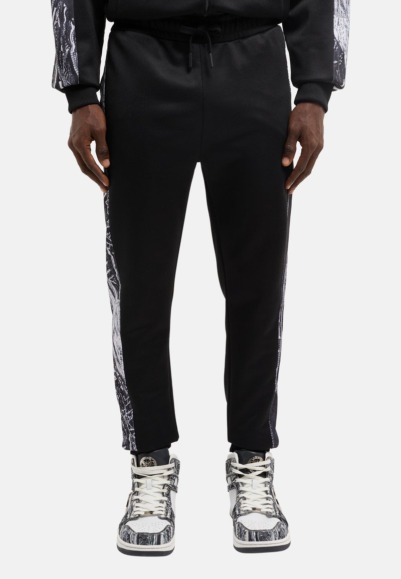 Sorte sweatpants med en tætsiddende pasform, der har teksturerede hvide grafiske mønstre langs siderne og en justerbar talje for komfort.