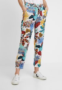Pantaloni leggeri ed elasticizzati con un vivace motivo di foglie tropicali. Presentano tasche laterali e una vita regolabile con coulisse. I colori includono blu, rosso e giallo.