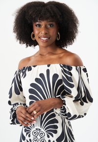 Off-the-shoulder dress in black and cream fabric featuring a large floral pattern, gathered sleeves, and a fitted bodice.