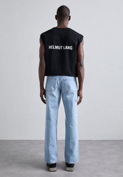 Top negru fără mâneci, scurt, cu "HELMUT LANG" imprimat în alb pe spate; asortat cu blugi drepti de culoare albastru deschis și pantofi cu platformă.