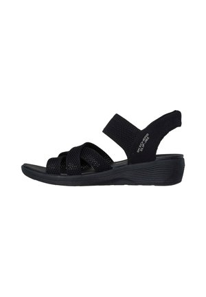 Sandalia negra de Skechers, sin tiras, con un bajo tacón cuña, que presenta anchas correas trenzadas y un diseño de punta abierta.
