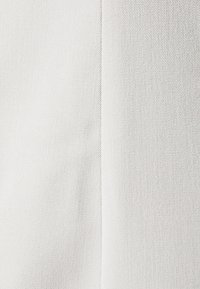 Biała tkanina z subtelnym, diagonalnym wzorem splotu. Gładka faktura z delikatnym połyskiem, przedstawiająca dwa połączone kawałki.