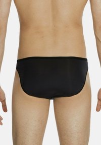 Slip da bagno neri realizzati in materiale liscio, con design a vita bassa, fascia elastica nera e copertura minima sul retro.