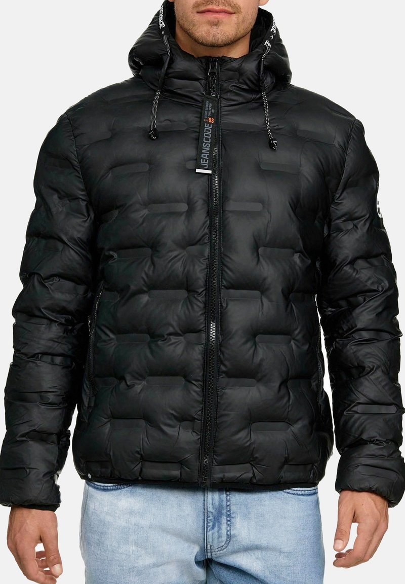 Giacca puffer nera con zip frontale, superficie testurizzata con sezioni trapuntate rettangolari, cappuccio regolabile e polsini elasticizzati.