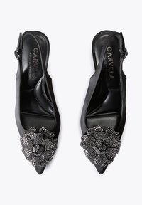 Talons aiguilles noires à bride arrière, avec un bout pointu, ornées d'une embellissement floral texturé en perles. Intérieur en cuir lisse.