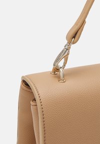 Béžová texturovaná kožená kabelka s elegantním obdélníkovým tvarem, vybavená kovovým zapínáním a hladkým, zaobleným uchycením popruhu.