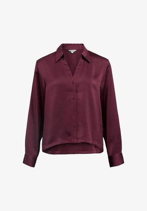Burgundy long-sleeve shirt in a smooth fabric, featuring a V-neck, front buttons, and a rounded hemline with cuffed sleeves.