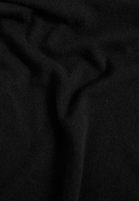 Sort strikket stof med en blød tekstur, der viser folder og blid drapering, med en ensartet farve gennemført med minimal lysreflektion.