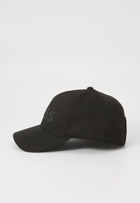 Casquette de baseball noire en tissu avec une visière courbée. Présente un logo ton sur ton à l'avant et des trous de ventilation sur les côtés.