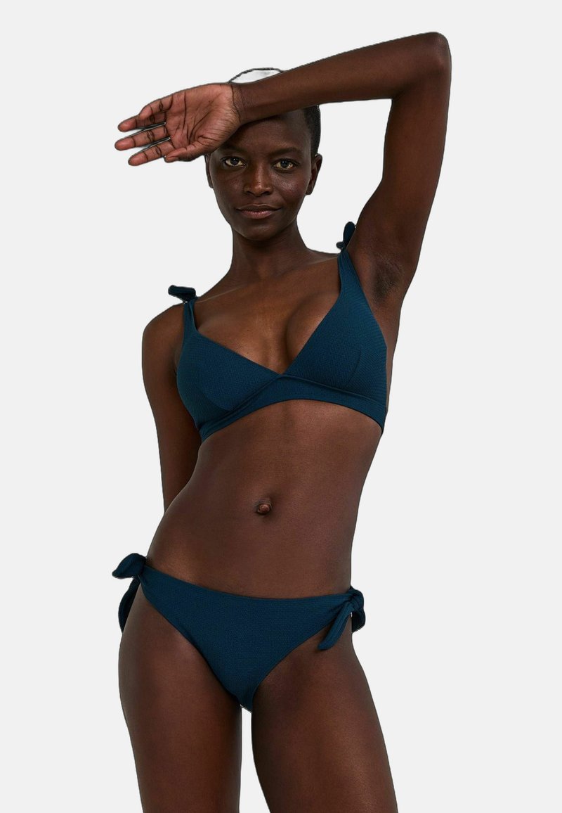 Ensemble de bikini bleu marine en tissu texturé, comprenant un bralette triangulaire avec des liens sur les épaules et un bas taille basse assorti avec des liens sur les côtés.