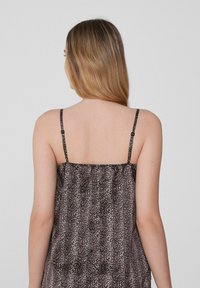 Top sin mangas con estampado de leopardo, con finas tirantes ajustables y un corte holgado. La tela es suave con una textura ligera y delicada.