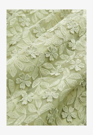 Hele roheline tikitud kangas, millel on keerukad lille- ja lehemustrid, koos tekstuurse ja läbipaistva disainiga.
