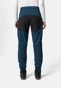 Blauwe en zwarte outdoor broeken met een gestructureerde afwerking, tapered fit en versterkte kniestukken, voorzien van een hoge tailleband en enkelboorden.