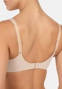 Beżowy biustonosz z gładkiego materiału, regulowanymi ramiączkami i zapięciem na plecach. Charakteryzuje się prostymi liniami i minimalistycznym designem, co zapewnia wszechstronność.