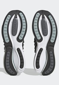 Les semelles de baskets noir et blanc présentent un design en caoutchouc texturé avec des accents gris. Comprend des pods et des rainures pour une adhérence et un soutien améliorés.