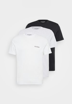 Drie crew neck t-shirts in het wit, grijs en zwart, gemaakt van katoen. Elk shirt heeft een subtiele "GUESS"-logo op de borst.