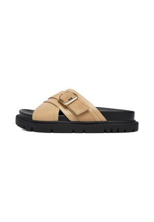 Beige slidssandal med sort sål, brede krydsremme og justerbar spænde på toppen, med en chunky mønstret ydersål.